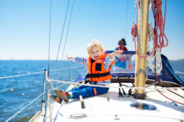 a young boy with a lifejacket on a sailboat
