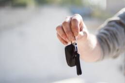 a while male handing over a set of car keys