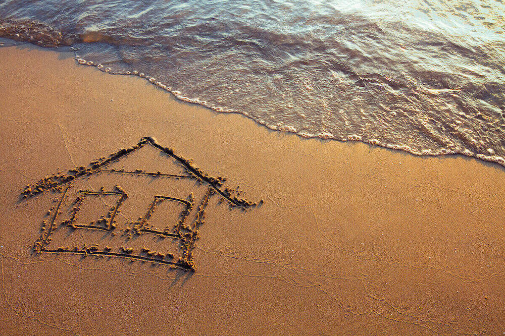 a house drawn in sand on a beach