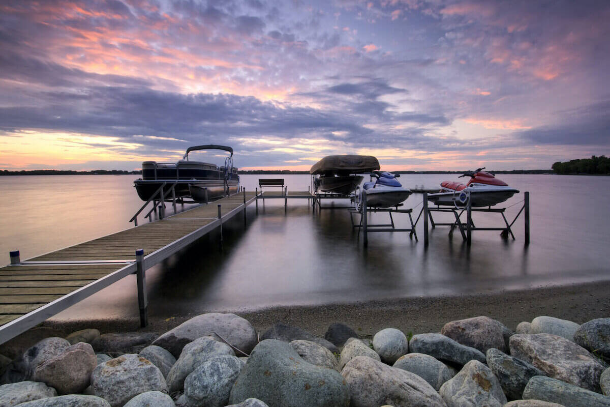 two boats and two jet skis on a dock at sunset time